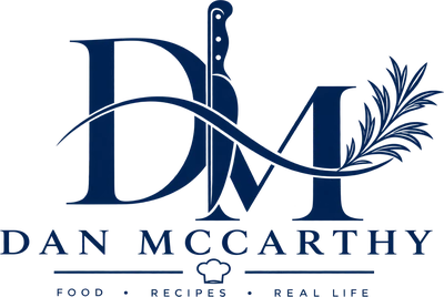 Dan McCarthy logo: DM monogram with a chef's knife and rosemary. Food, recipes, real life.